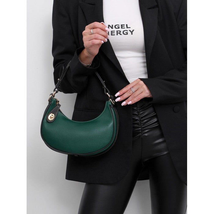 A person holding a green Noemi leather handbag with a vintage brass hardware and a Pebble grain texture.