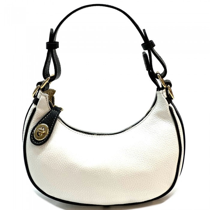 A white Noemi leather handbag with a pebble-grain texture, featuring a crescent shape, vintage brass hardware, a detachable shoulder strap, and a top handle.