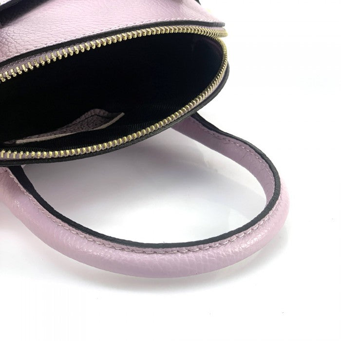 A partial view of a pink Bellaria Italian leather shell bag, showcasing the gold-tone zipper and a double top handle.
