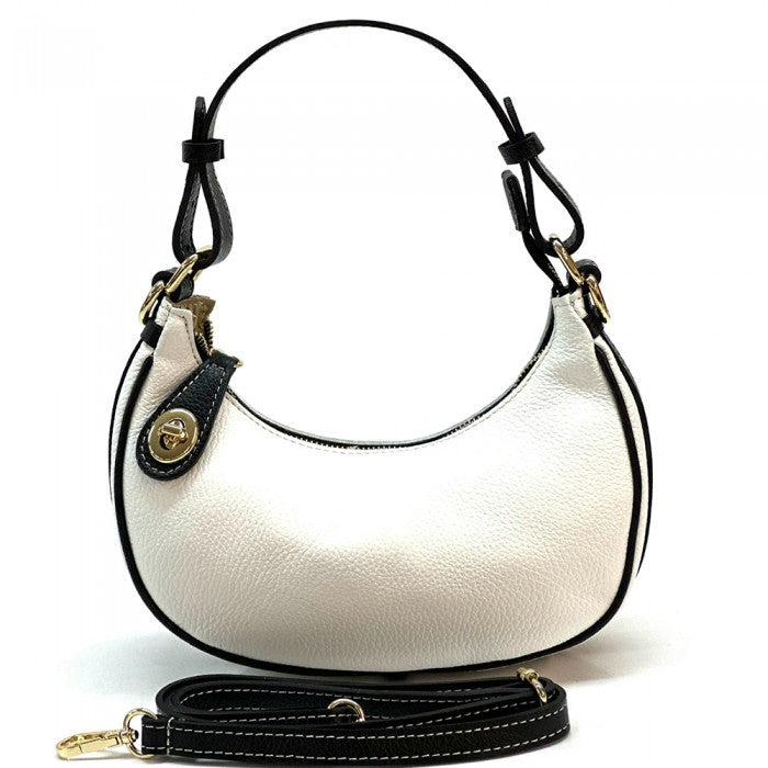 A white Noemi leather handbag with a pebble-grain texture, featuring a crescent shape, vintage brass hardware, a detachable shoulder strap, and a top handle.